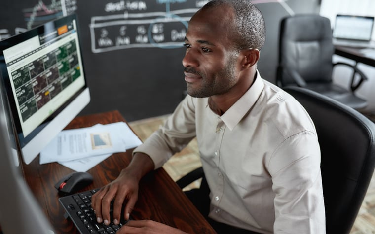 Man sitting in front of several screens trading stocks.