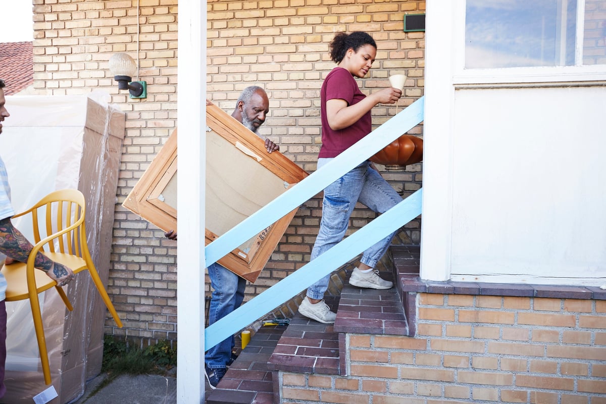 A family carries various furniture into their new house.