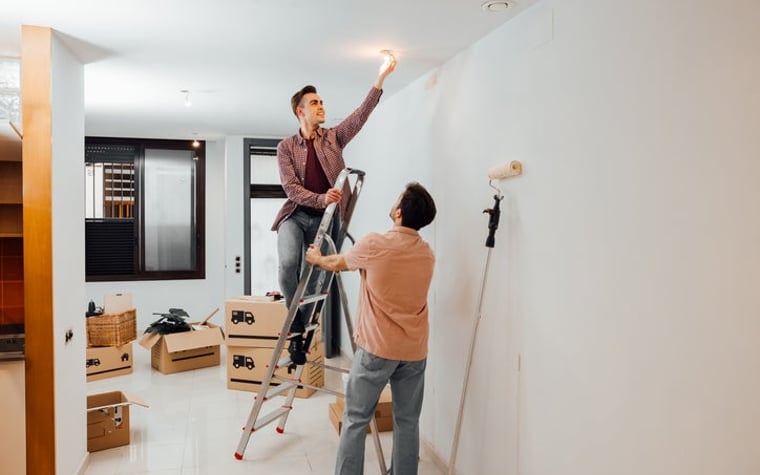 Young couple fixes a light bulb as they move into their new house.