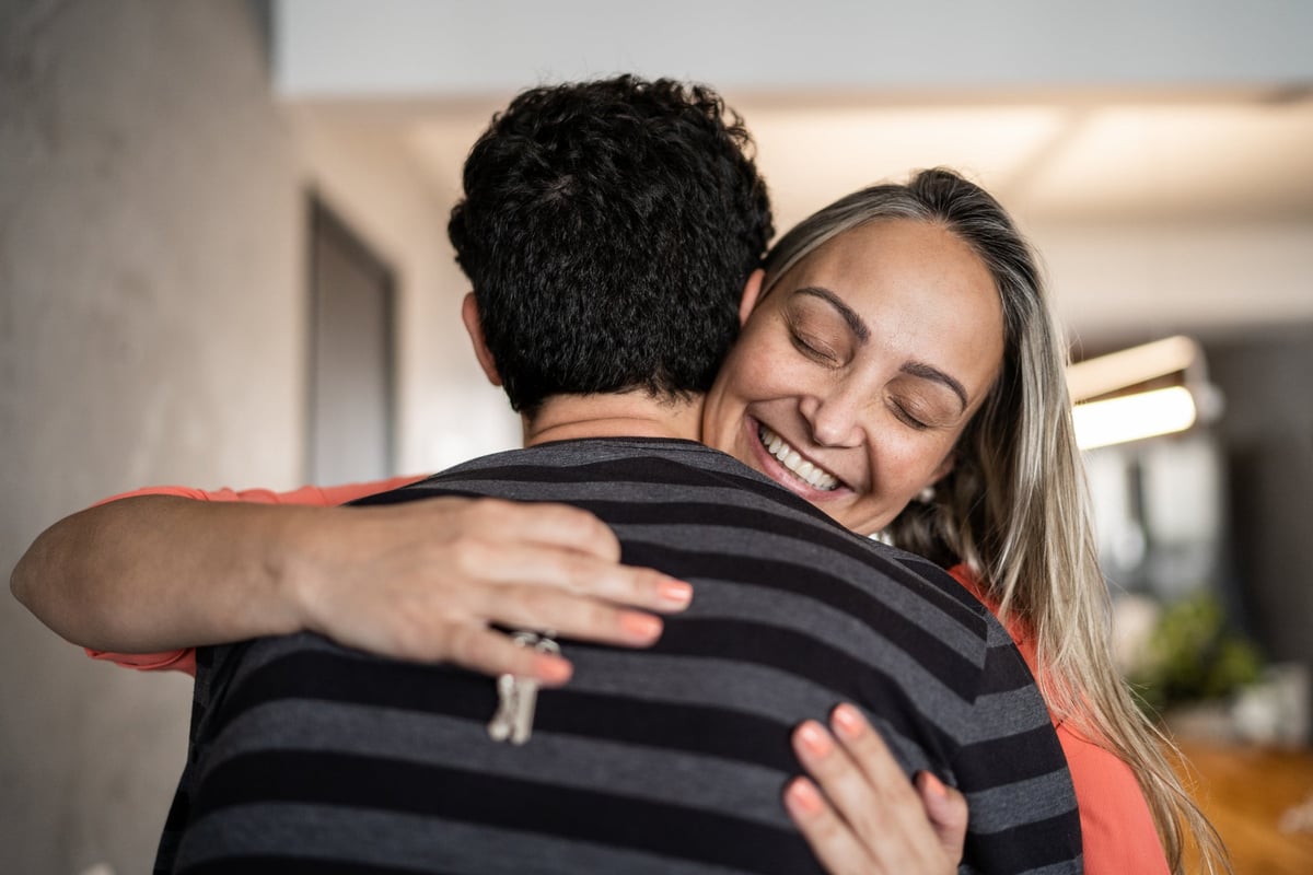 A couple embraces happily while one person holds a house key.