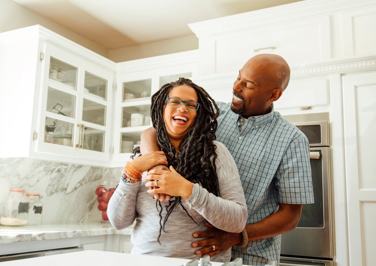 A middle-aged couple embraces happily in a kitchen.