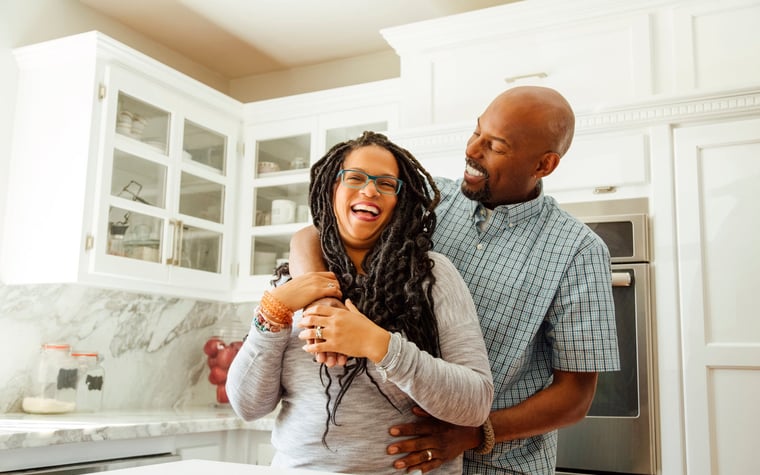 A middle-aged couple embraces happily in a kitchen.