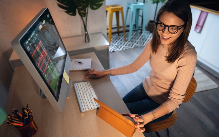 A young adult tracks and trades stocks on a computer.