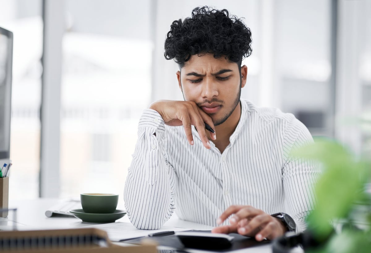 A young man with a frown uses a calculator