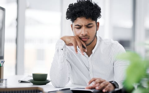 A young man with furrowed brow uses a calculator