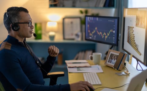 A cryptocurrency trader wearing a headset is on a video call from a home office.