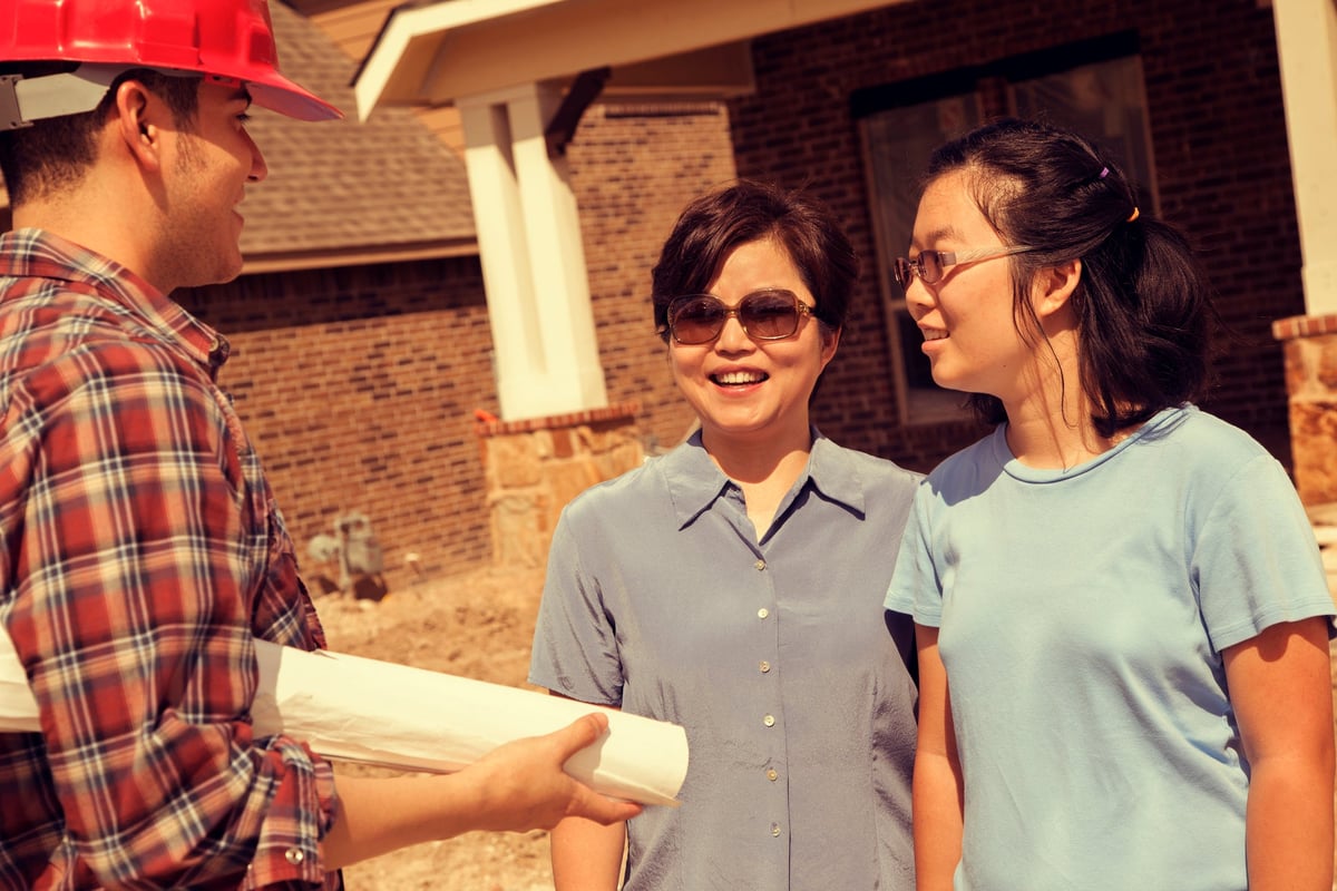 New home buyers discuss plans with the building contractor on the property.
