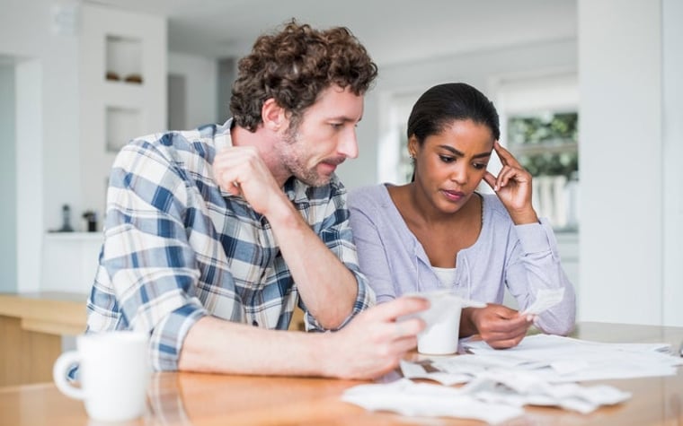 A couple looks at paperwork worriedly inside.