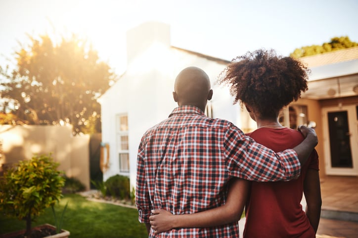 Happy couple looks at their home while the sunsets