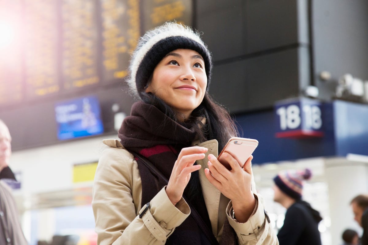 A visitor uses their smartphone as they wait for a train to arrive in a railroad station.