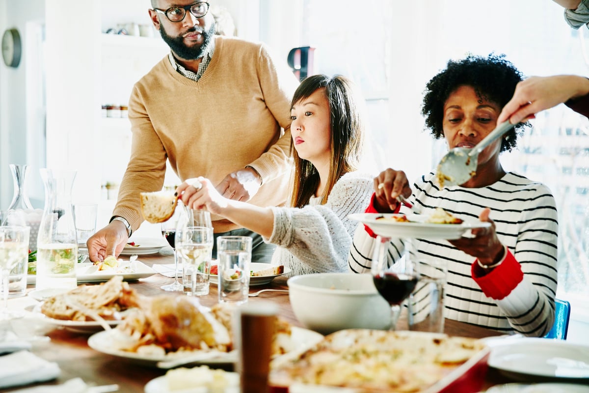 Friends and family serve each other food during a holiday dinner.