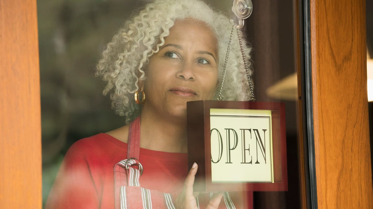 Une Personne Détient Le &Quot;Ouvrir&Quot; Signez Sur La Porte D’entrée D’une Petite Entreprise.