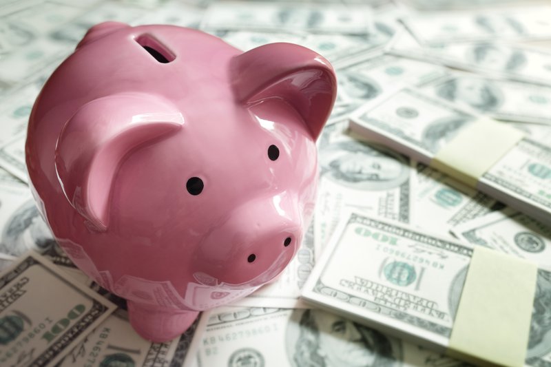 Piggy bank surround by cash stacks.