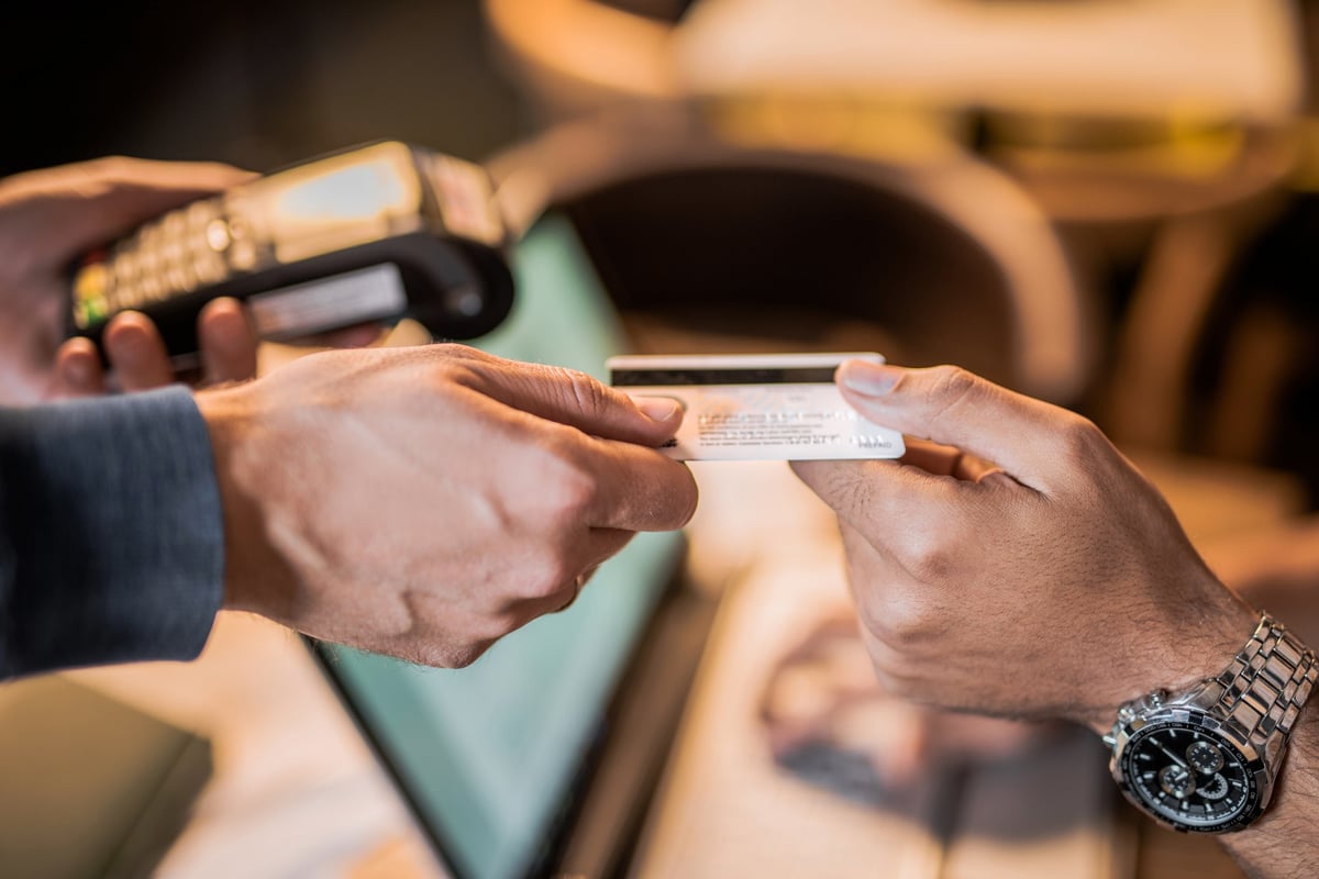 One hand passing a credit card to another hand.