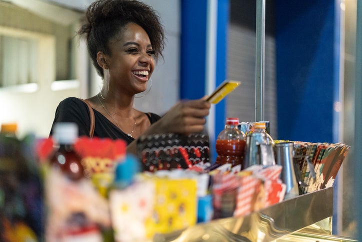 A young woman buys food from a street vendor using a credit card.