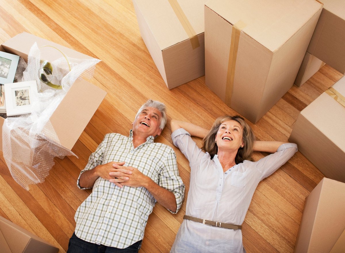 Happy, mature couple laying on the floor surrounded by moving boxes.