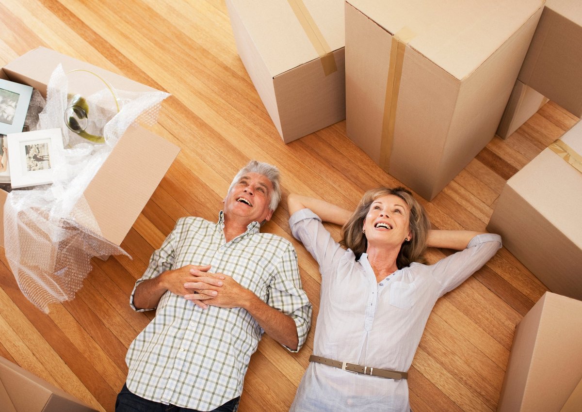 Happy, mature couple laying on the floor surrounded by moving boxes.