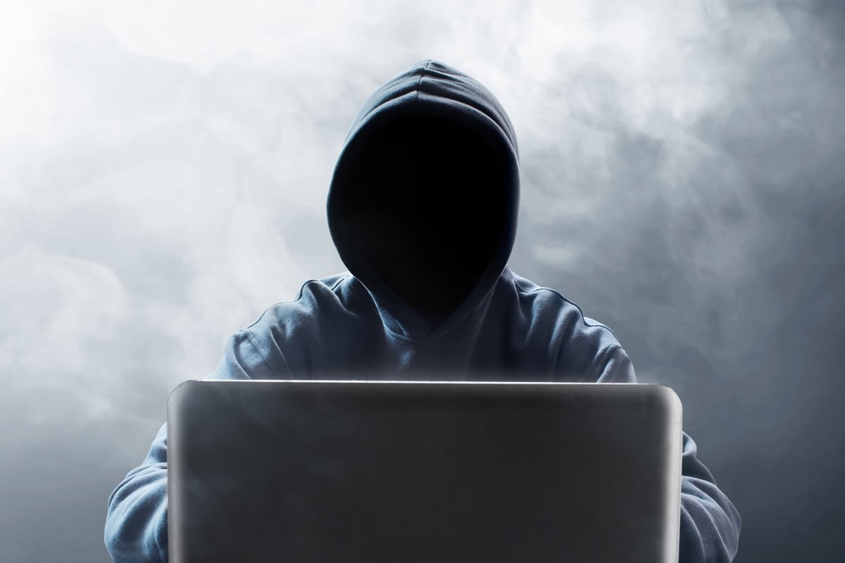 Hooded figure at laptop