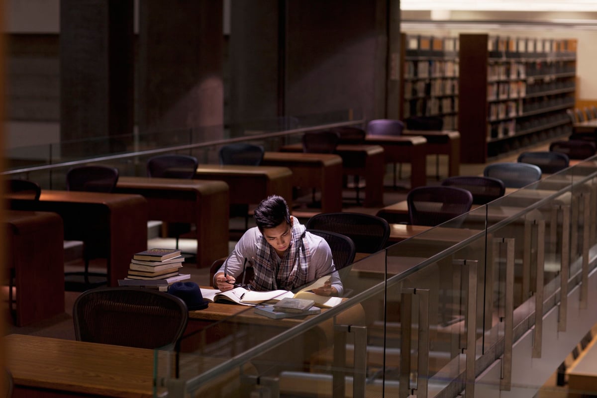 A male college student studying alone in a library.