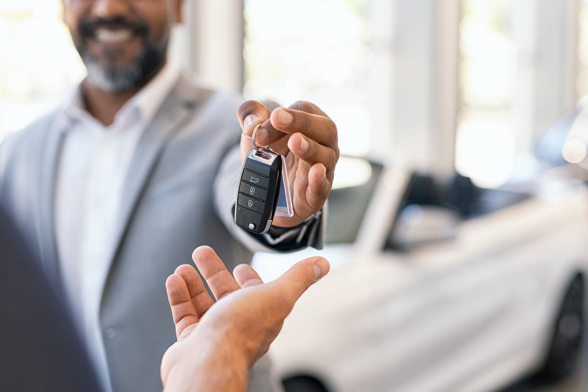 A salesman handing over the keys to a new car.