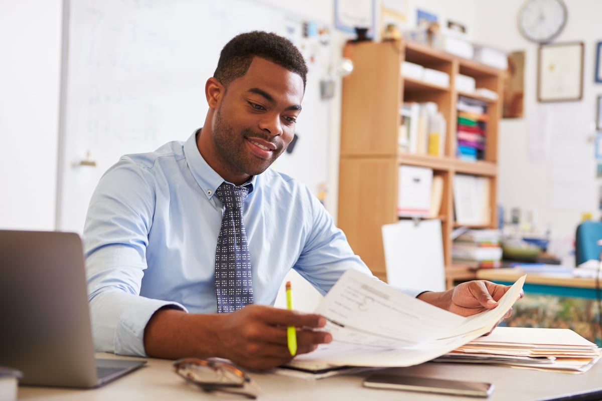 A man reading paperwork at his desk.