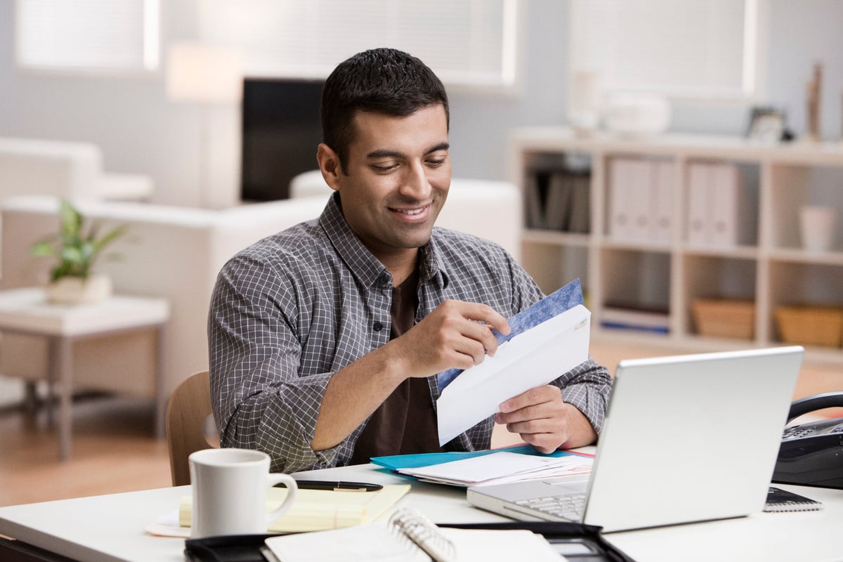 Man smiling at the contents of an open envelope.