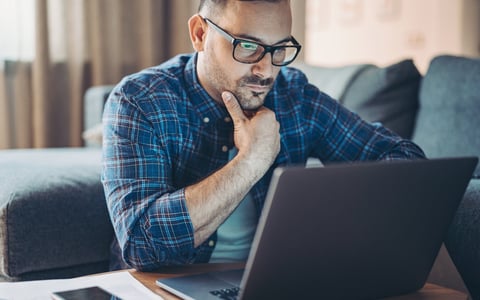 Man with glasses looking at laptop.