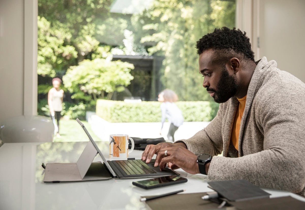 A man works out of his home office while his two children play outside.
