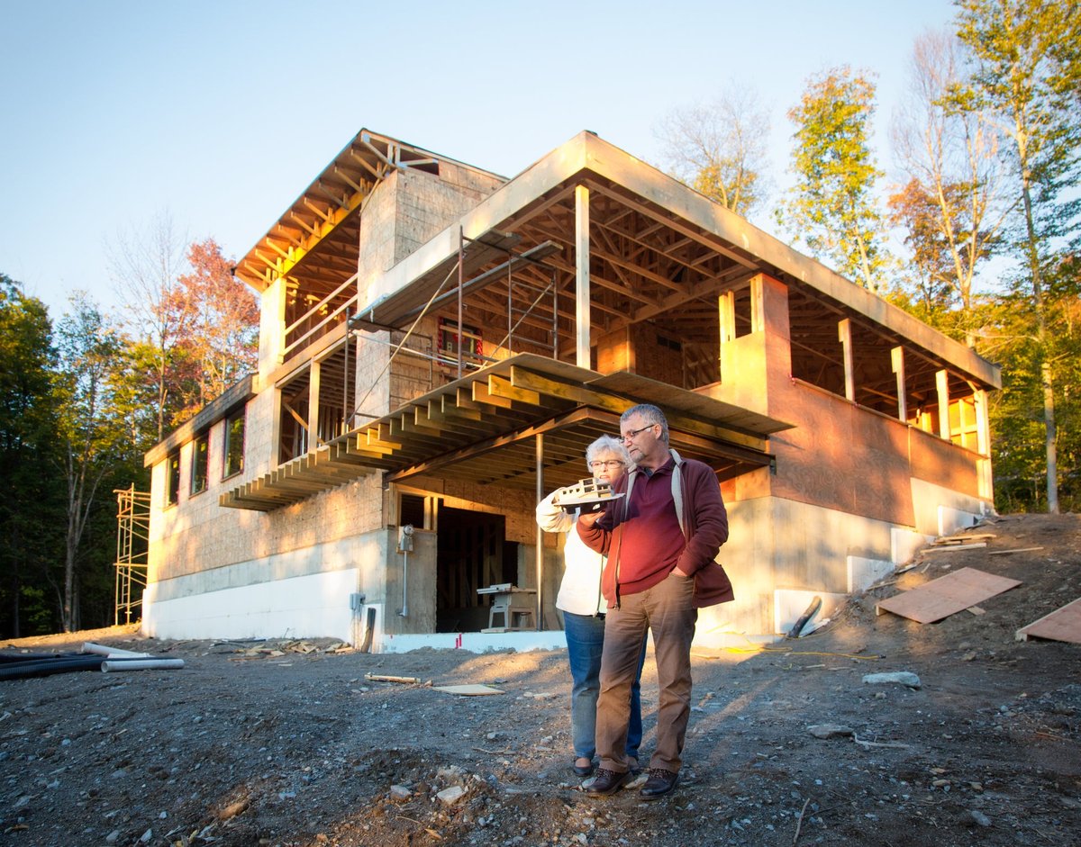 Mature couple talking in front of partially-constructed home.
