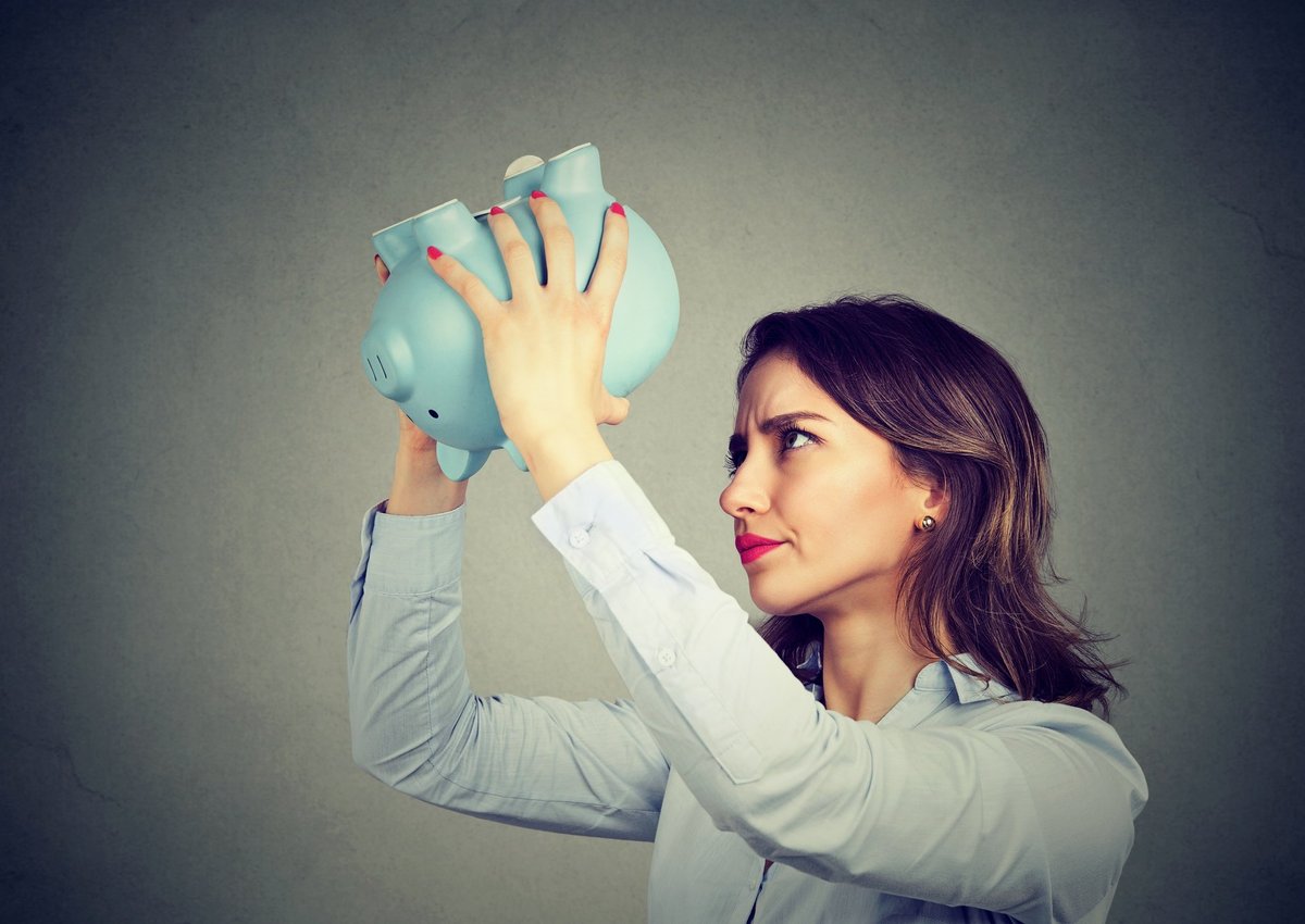 woman holding empty piggy bank upside down