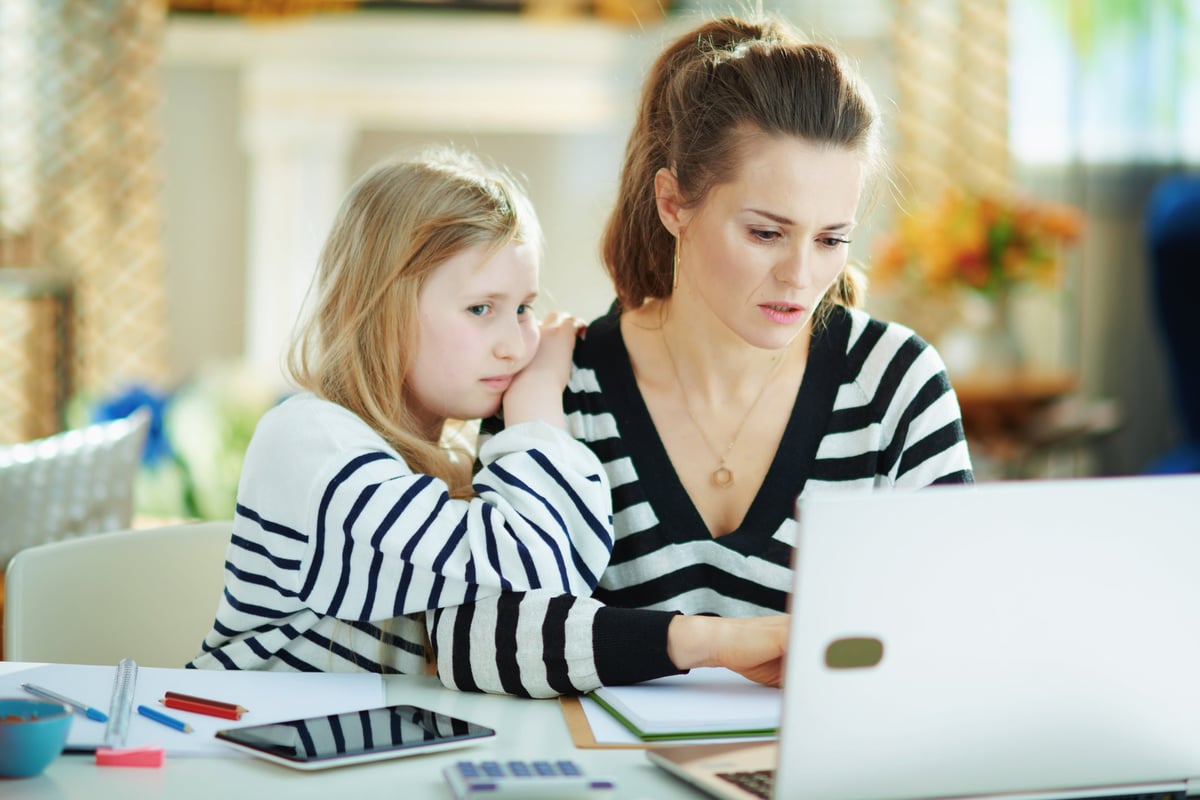 A mother and daughter look sadly at a computer screen.