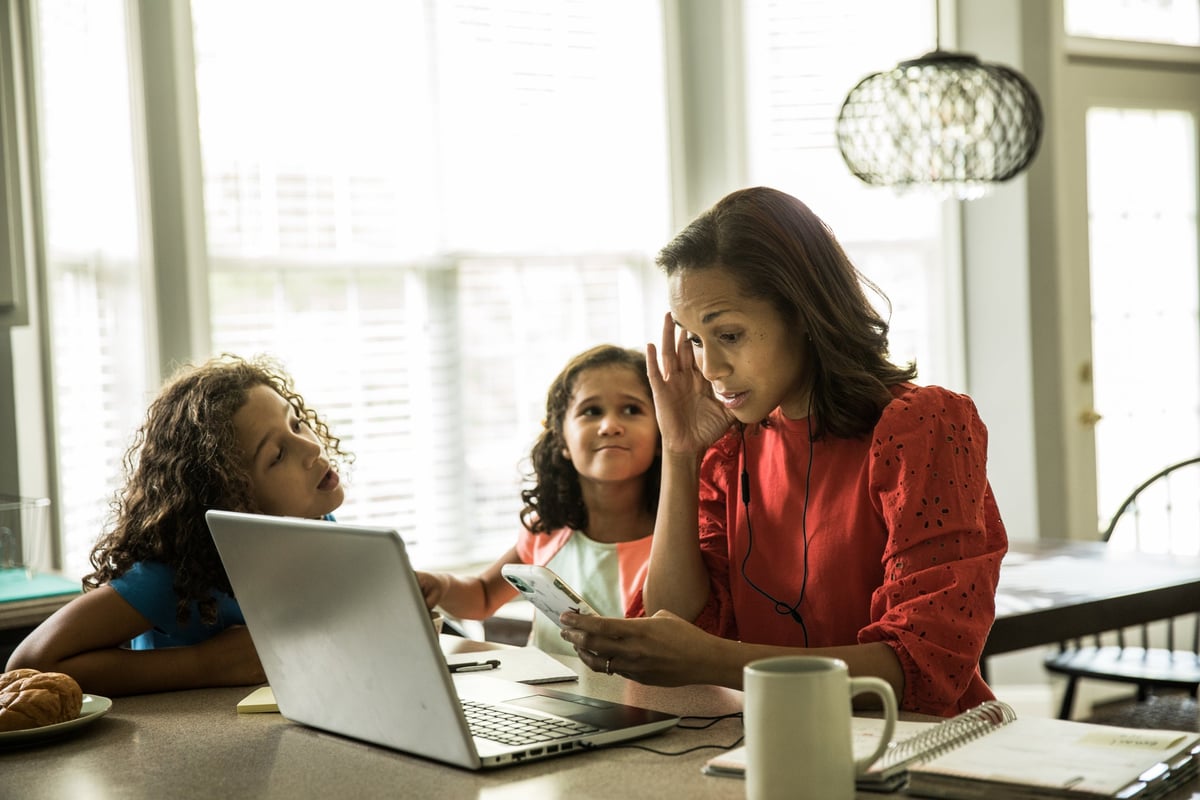 Mother working from home with young children nearby