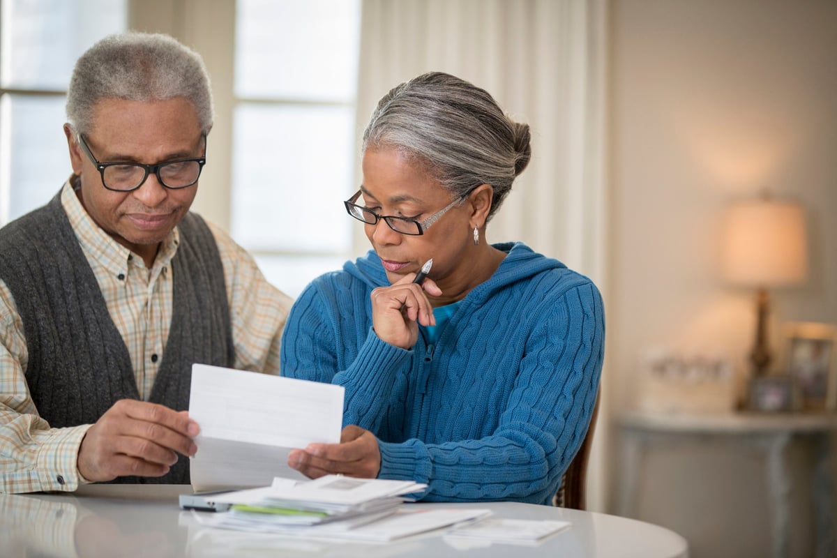 An older couple sit at a table and go over their finances.
