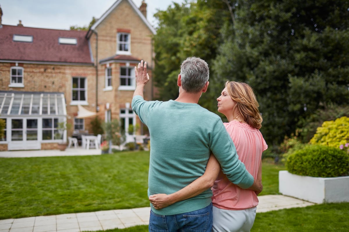 An older couple, searching for a new home, look at the back of a property