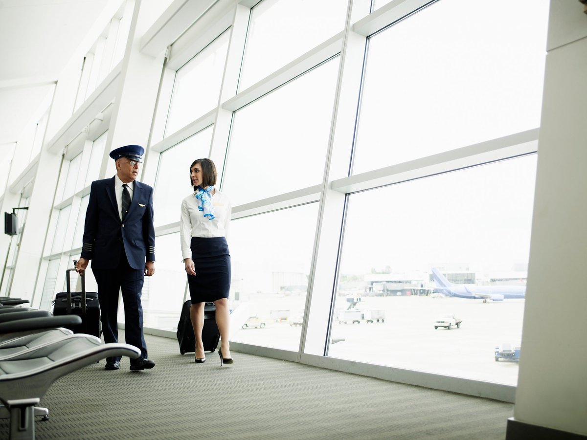 Pilot and flight attendant walking to airport gate.