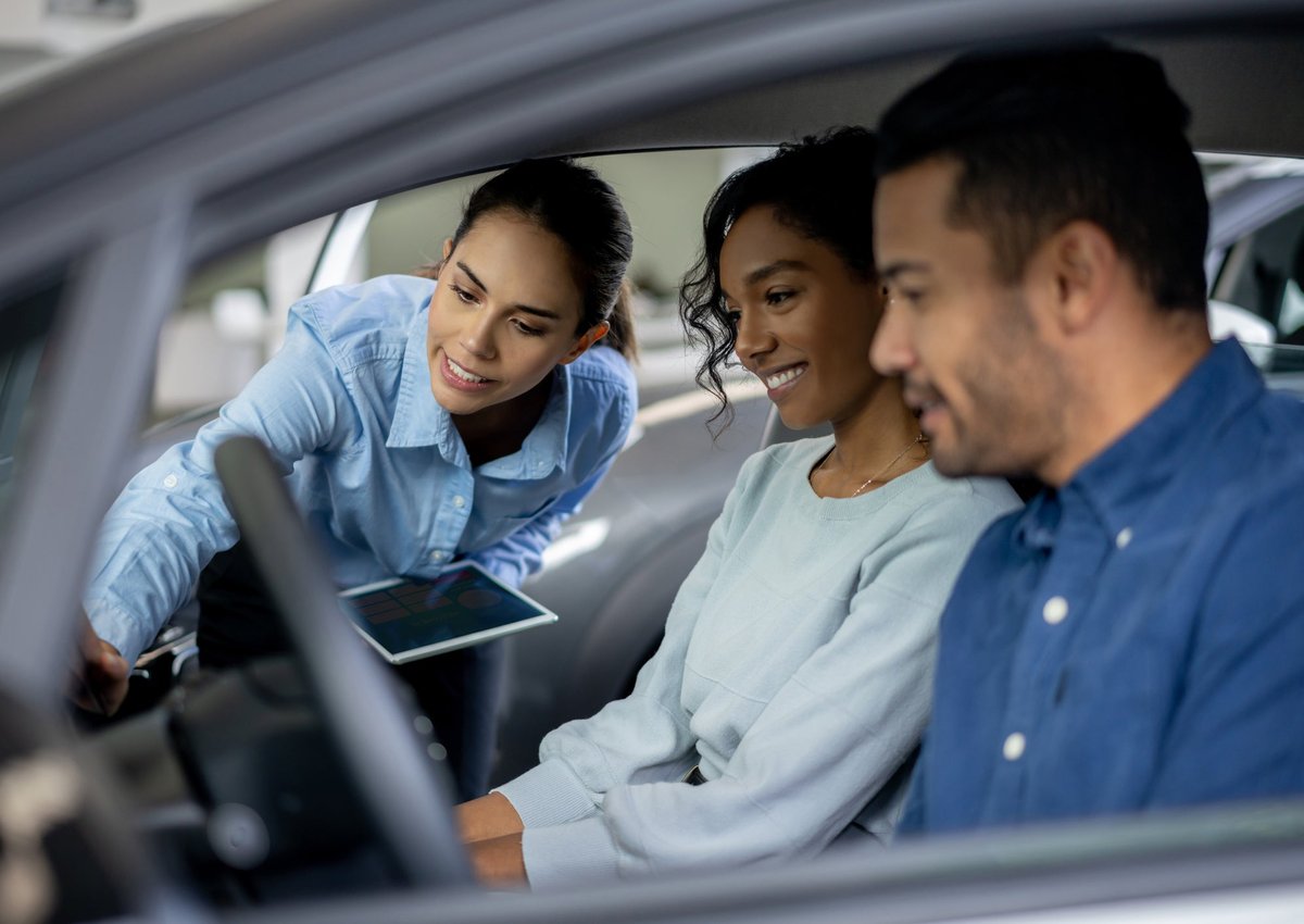 Salesperson showing couple features inside a car.