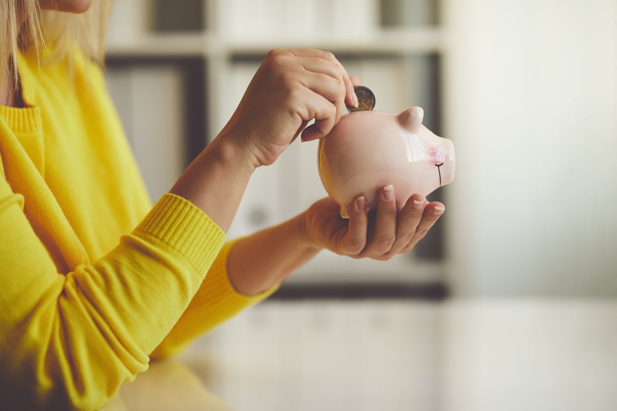 Woman putting coin in piggy bank.
