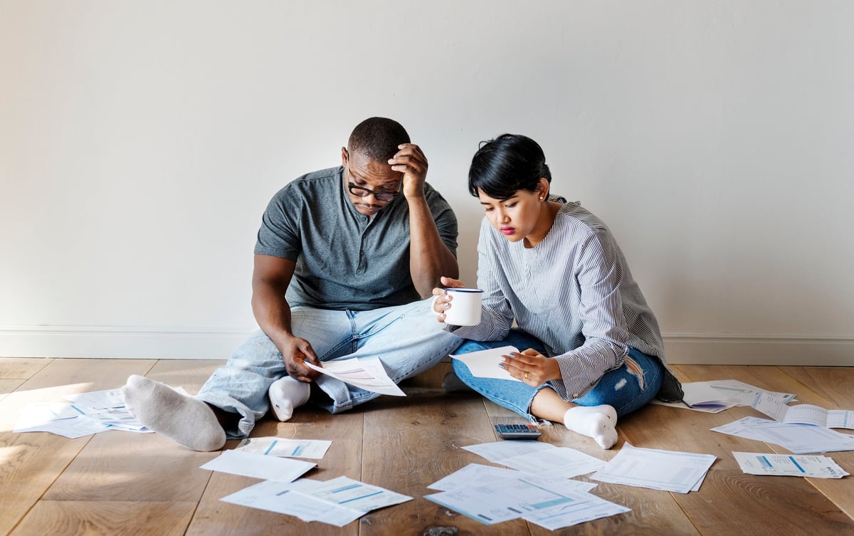 Distressed young couple sitting on the floor surrounded by documents
