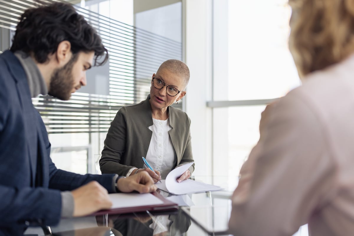 A woman reviews a couple's financial statments at a round conference table