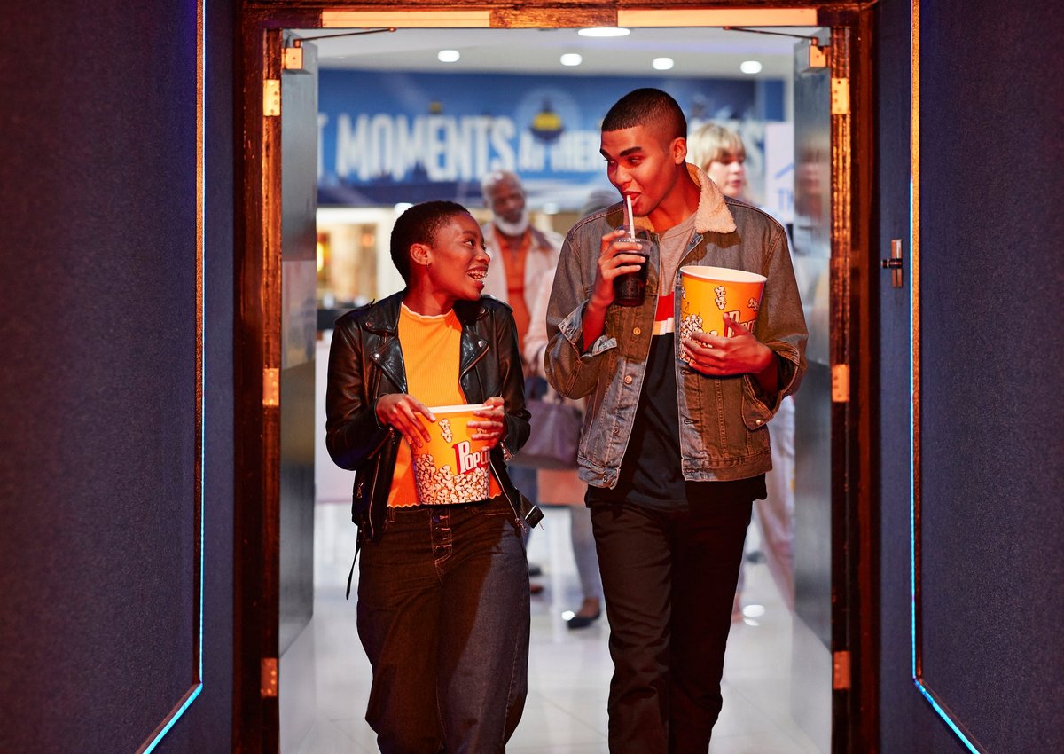 Two smiling friends head into a movie theater.