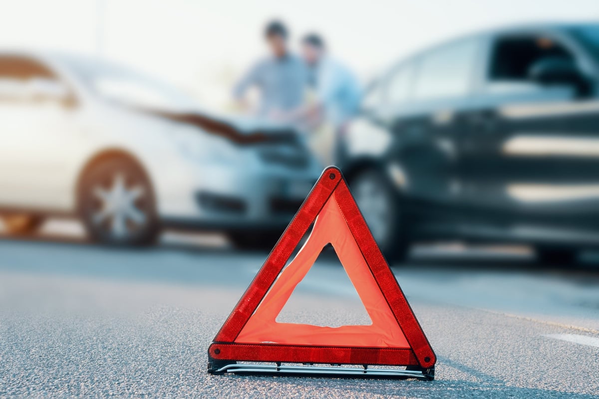 Two men standing at their cars discussing a fender bender.