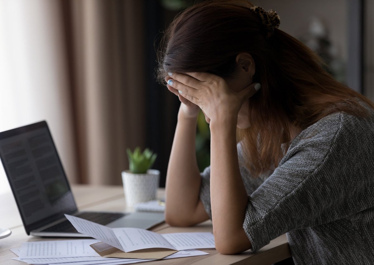 Woman appearing upset with head in her hands as she reads letter.