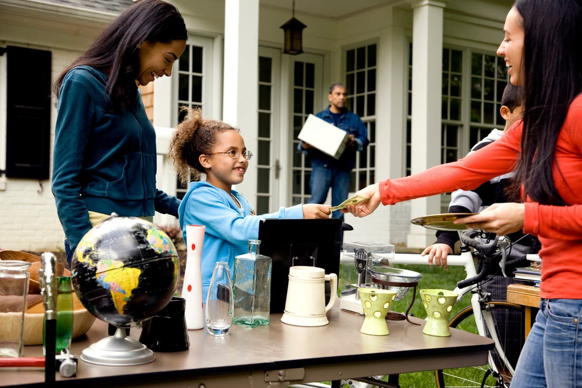 Woman buying items at a yard sale with cash.