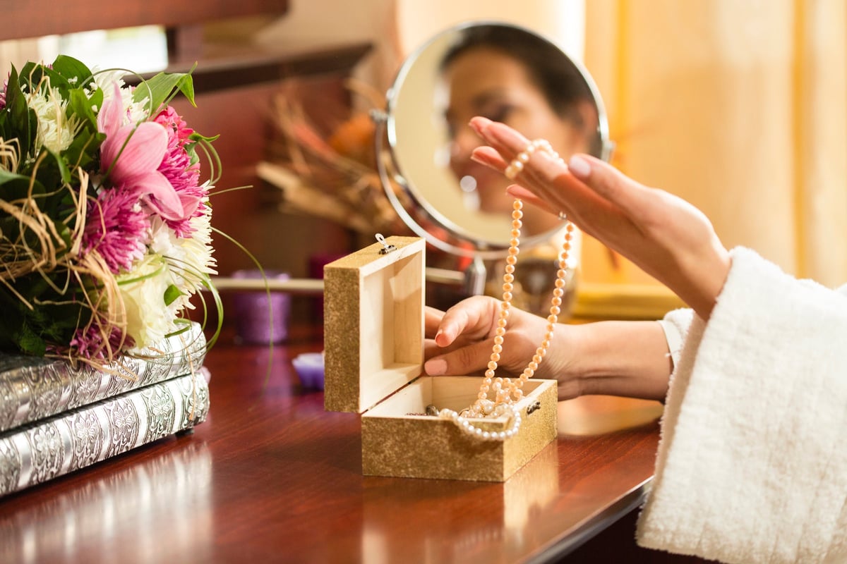 Woman choosing necklace from jewelry box.