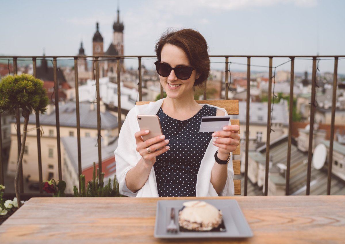 Woman holding her credit card and smiling while she dines in Europe