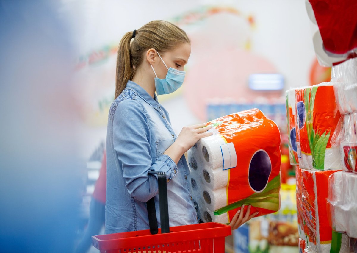 Woman in mask buying paper products from the grocery store.