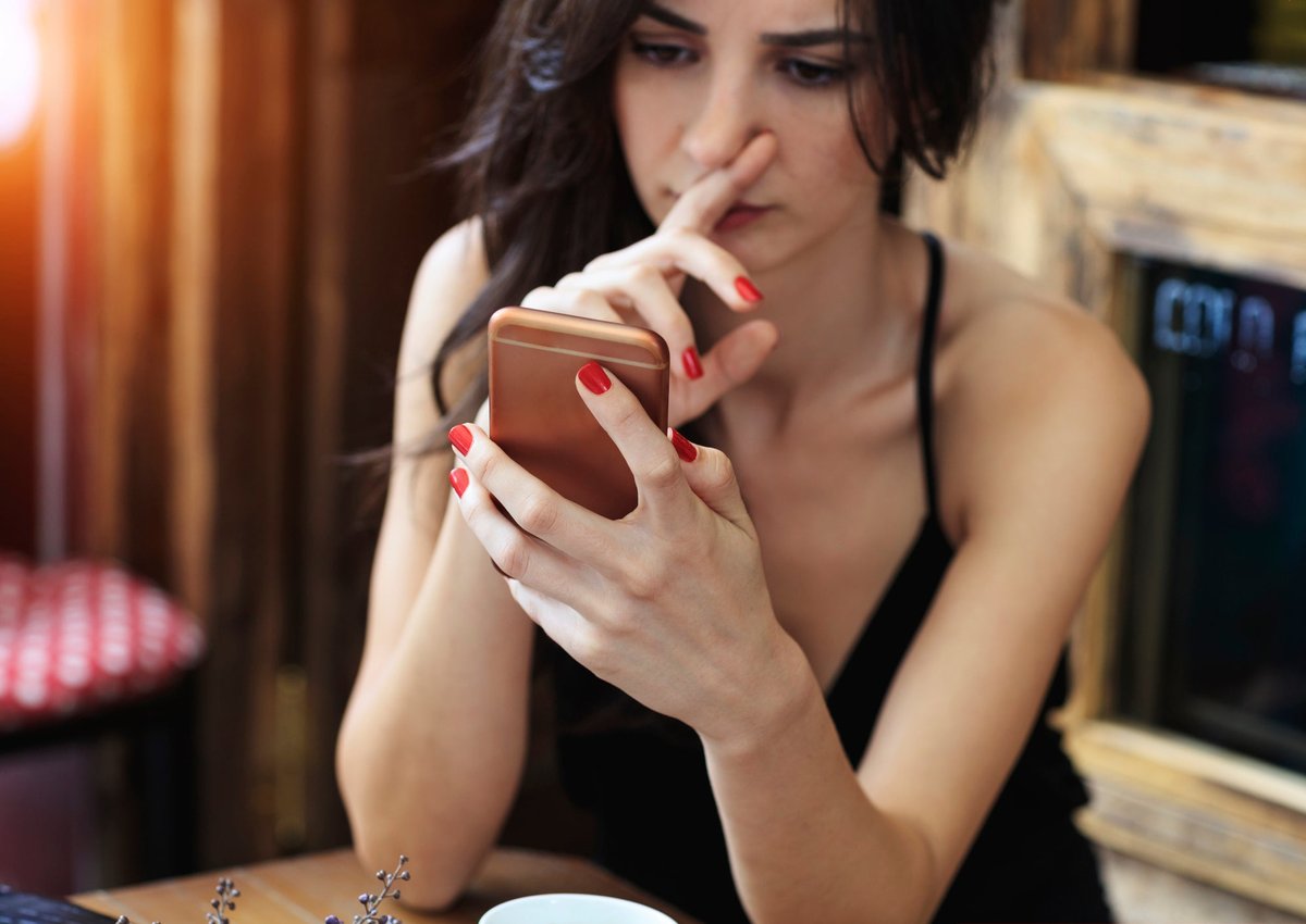 Woman looks skeptically at her cellphone.