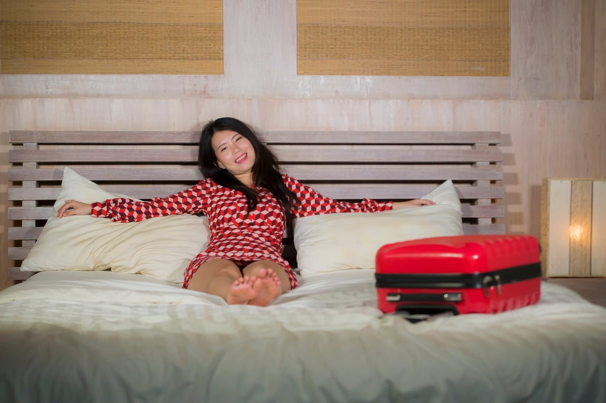 Woman lounging on a bed with her luggage.