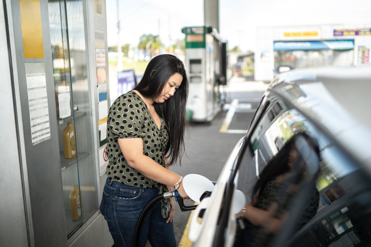 Woman refueling her car at a gas station.