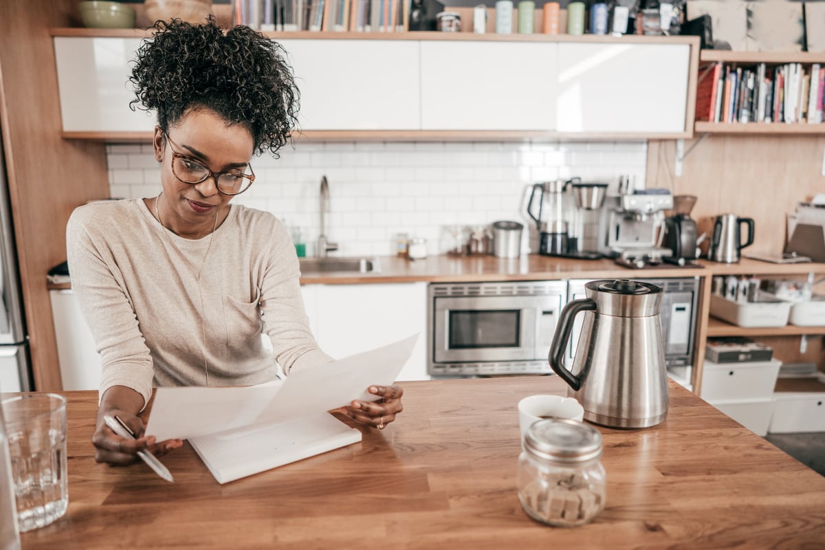 A woman sits in her kitchen, going over her personal finances.